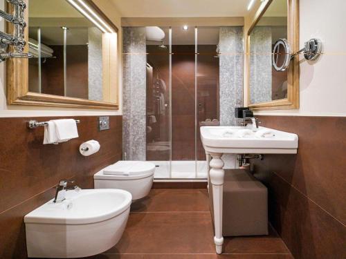 a bathroom with two sinks and a toilet and a shower at Papadopoli Hotel Venezia - MGallery Collection in Venice