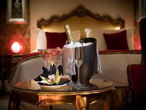 a table with wine glasses and a plate of food at Papadopoli Hotel Venezia - MGallery Collection in Venice