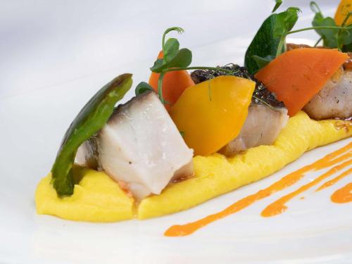 a plate of food with meat and vegetables at Papadopoli Hotel Venezia - MGallery Collection in Venice