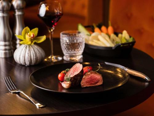 a black plate with meat and fruit on a table at Sofitel Luxembourg Europe in Luxembourg