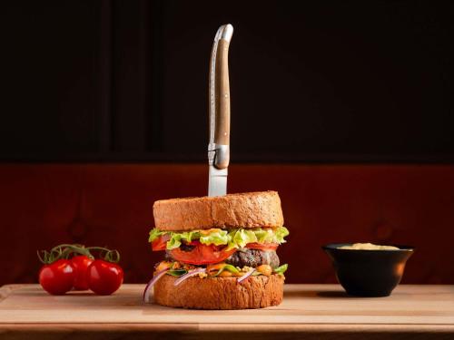 a sandwich with a knife on a cutting board at Sofitel Luxembourg Europe in Luxembourg