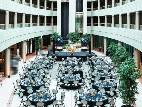 a cafeteria filled with tables and chairs in a building at Sofitel Luxembourg Europe in Luxembourg