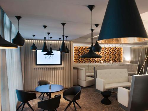 a lobby with a couch and a table and chairs at Sofitel Luxembourg Europe in Luxembourg