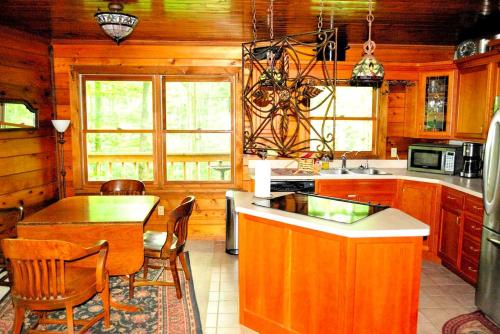 a kitchen with a table and a kitchen with wooden walls at Wooded & Fabulous Brown County Cabin with Hot Tub Near Nashville, IN in Nashville
