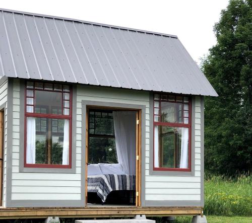 a tiny house with a gray roof and windows at Runamuk Farm Camp with a View near the Adirondacks in Buskirk