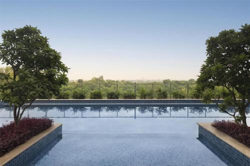 una piscina con árboles y una valla en Radisson Hotel Delhi MG Road, en Nueva Delhi