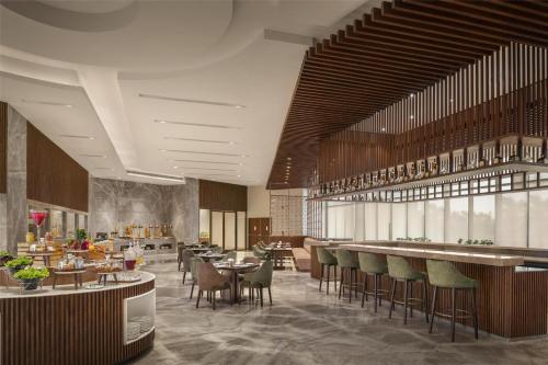Un restaurante con mesas y sillas y un bar. en Radisson Hotel Delhi MG Road, en Nueva Delhi