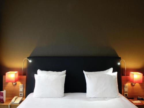 a bedroom with a bed with two pillows and two lamps at Mercure Hotel Den Haag Central in The Hague