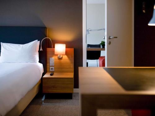 a bedroom with a bed and a desk with a lamp at Mercure Hotel Den Haag Central in The Hague