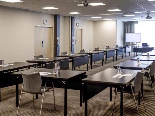 a conference room with tables and chairs and a screen at Mercure Hotel Den Haag Central in The Hague