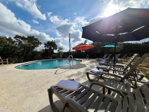 a group of chairs and umbrellas next to a pool at Entire Property Rental for Large Groups Sleeping 40+ Guests with Pool and Fire Pit in Texas Hill Country near Austin, Texas in Hammetts Crossing