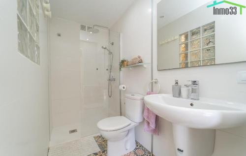 Un baño blanco con inodoro y lavabo. en Apartamento Sol del Mar, en Villajoyosa