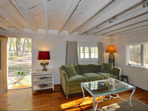 Una sala de estar con un sofá verde y una mesa. en Idyllic Getaway Cottage in the Woods near Woodstock, New York, en Woodstock