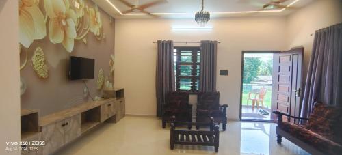 a living room with a couch and a tv on the wall at His Grace Premium Home - Nr to Malpe Beach in Udupi