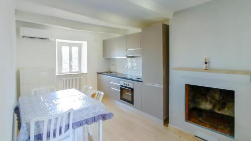 een witte keuken met een tafel en een open haard bij Casa Vacanze - Il Gelso in Collevecchio