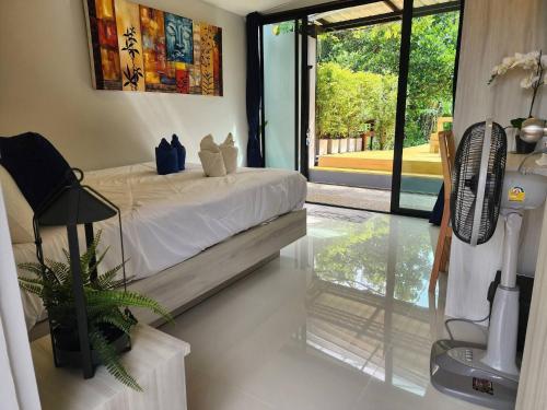 a bedroom with a bed with a fan and a window at Pool Villa Suchada 3 bedrooms max 7 peoples in Ban Khlong Haeng