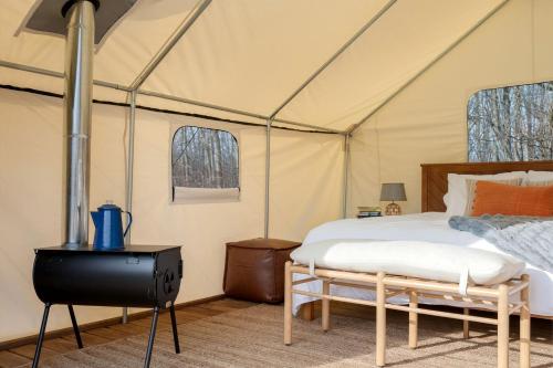 a tent with a bed and a stove in a room at Fabulous Michigan Glamping Getaway near South Haven in Lacota