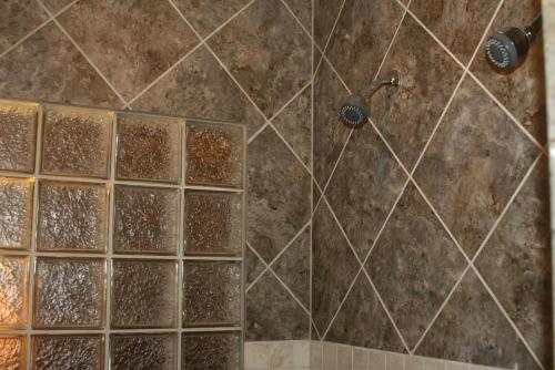 a bathroom with a shower with brown tiles at Romantic One-Bedroom Cabin with a Fireplace near Asheville, North Carolina in Crabtree