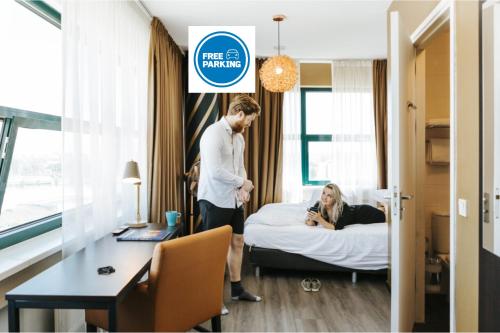 a man standing in a hotel room with a woman laying on a bed at The Hague Teleport Hotel in The Hague