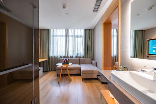 a bathroom with a couch and a sink and a living room at Qiuguo Hotel Beijing Convention Center Bird's Nest Beiyuan in Beijing