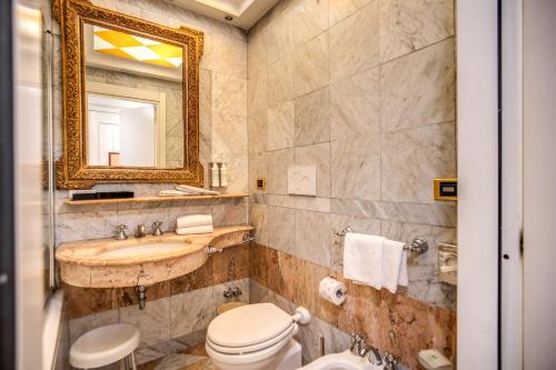 a bathroom with a sink and a toilet and a mirror at The Britannia Hotel in Rome