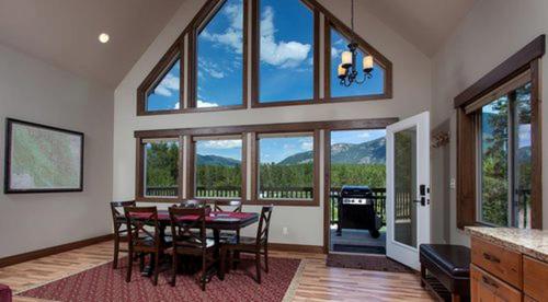 a dining room with a table and chairs and windows at Charming Mountain Cabin for a Family Getaway near Lake McDonald, Montana in West Glacier