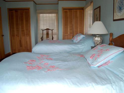two beds with white sheets with pink flowers on them at Waterfront Vacation Rental with a Hot Tub and Dock on Edisto Island, South Carolina in Edisto Island