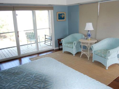 a living room with chairs and a table and windows at Waterfront Vacation Rental with a Hot Tub and Dock on Edisto Island, South Carolina in Edisto Island