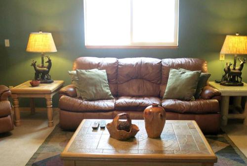 a living room with a brown leather couch and a table at Impressive Cabin Rental with Views of Pike National Forest near Colorado Springs, Colorado in Westcreek