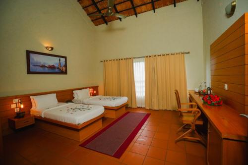 a hotel room with two beds and a desk and a desk at Vaidekam Resorts & Wellness, Kannur in Kannur