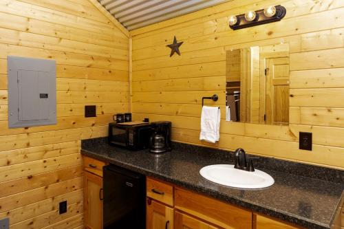 a bathroom with a sink and a microwave at Memorable Family Vacations in this Charming Log Cabin Rental in Texas State in Pipe Creek