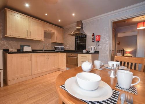 a kitchen with a wooden table with white cups on it at The Queens Hotel & Victoria Cloisters Apartments in York