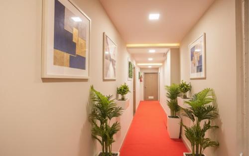 a corridor with a red carpet and potted plants at FabExpress Silver Lake - Nr BKC in Mumbai