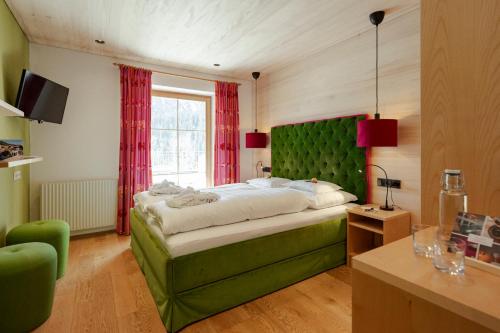 a bedroom with a green bed and a window at Hotel Stäfeli in Lech am Arlberg