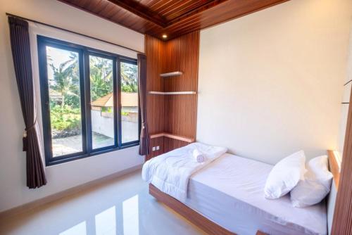 a bedroom with a bed and a large window at Tutde Guest House in Bringkit