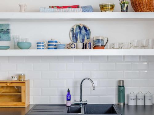a kitchen counter with a sink and a shelf with dishes at 1 Bed in Polruan 83945 in Fowey