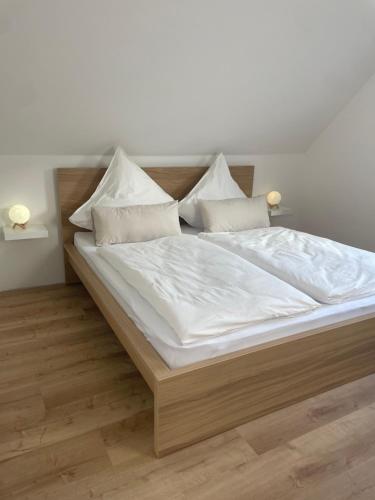 a large bed with white sheets and pillows on it at Haus87a in Oberkirch