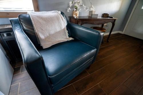 a blue leather chair in a living room with a table at Serene Loft Cabin with Outdoor Grill and Fire Pit in Creal Springs, Illinois in Sunset Harbor