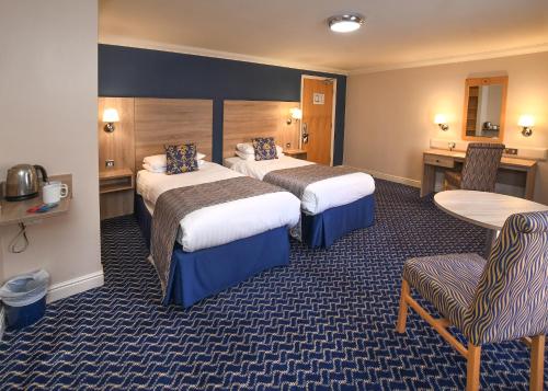 a hotel room with two beds and a table and chairs at The Queens Hotel & Victoria Cloisters Apartments in York