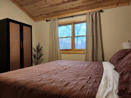 a bedroom with a large bed and a window at Cozy Rustic Cabin with Hot-Tub Ideal for a Couples Retreat in Illinois in Etherton