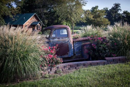 an old truck parked in a garden with flowers at Cozy Rustic Cabin with Hot-Tub Ideal for a Couples Retreat in Illinois in Etherton