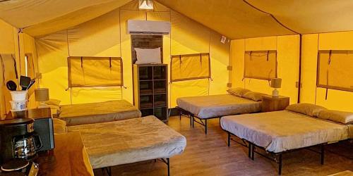 a room with three beds in a yellow room at Impressive Safari Tent with Barbecue in Staples, Texas in Staples