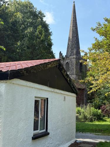 a small white building with a church steeple in the background at The River Cottage 3 Bedroom retreat in Limerick