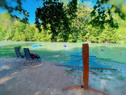 two chairs sitting on the shore of a lake at Impressive Safari Tent with Barbecue in Staples, Texas in Staples