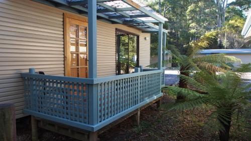 a front porch of a house with a blue railing at Strahan Retreat Holiday Park in Strahan
