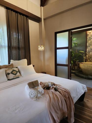 a bedroom with a large white bed with a window at Prana Siargao Resort in General Luna