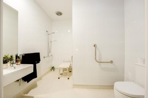a white bathroom with a shower and a toilet at 3 Bedroom 3 Bath Accessible Bathrooms in Melton South