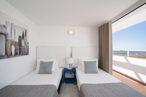 two beds in a room with a view of the ocean at Brisa Da Ria Apartment, Formosa Village in Fuzeta