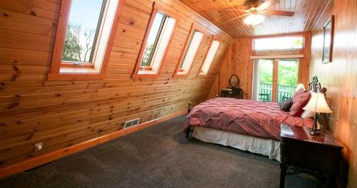 a bedroom with wooden walls and a bed in a room with windows at Romantic Forest Cabin with Amazing Private Deck and Spa in Ohio in Walnut Creek