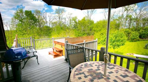 a deck with an umbrella and a table and a bench at Romantic Forest Cabin with Amazing Private Deck and Spa in Ohio in Walnut Creek